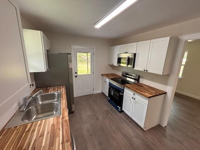 kitchen with wooden counters, a sink, stainless steel appliances, white cabinets, and dark wood-style flooring