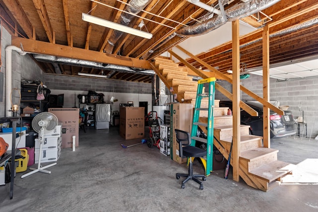 unfinished basement with concrete block wall, refrigerator, and stairway