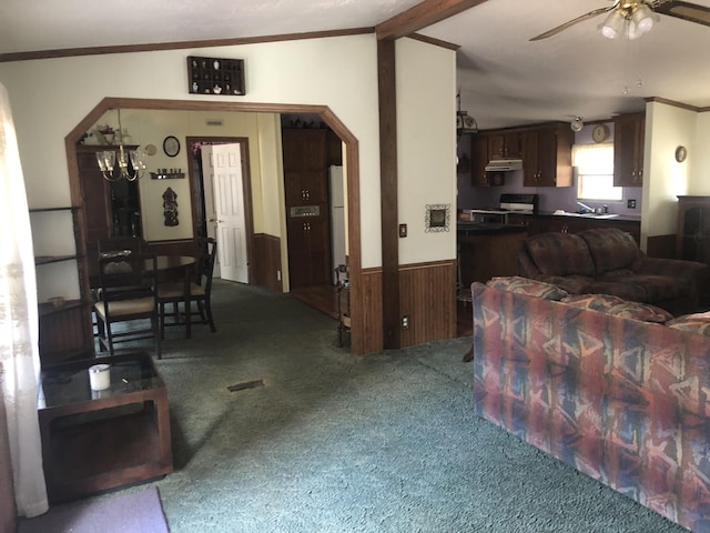 living area with a wainscoted wall, arched walkways, wooden walls, carpet, and crown molding