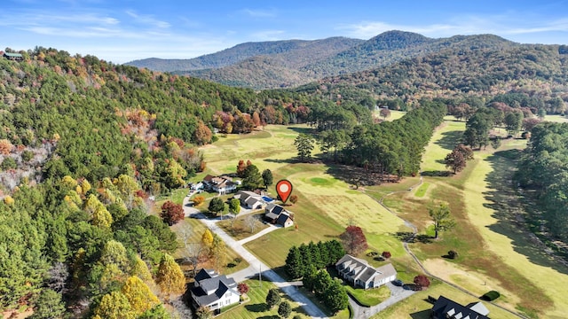 birds eye view of property with a wooded view, a mountain view, and view of golf course