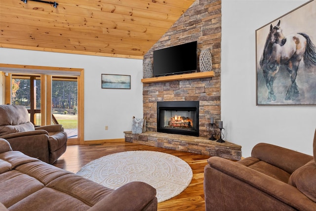 living room with baseboards, wooden ceiling, a stone fireplace, wood finished floors, and vaulted ceiling
