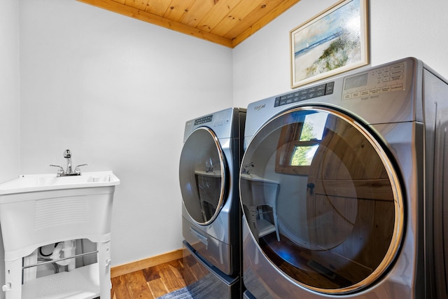 clothes washing area with baseboards, laundry area, washer and dryer, wooden ceiling, and wood finished floors