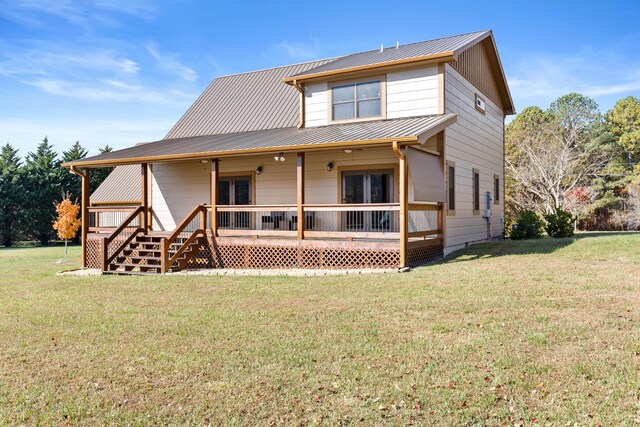 rear view of property with a standing seam roof, metal roof, a lawn, and covered porch