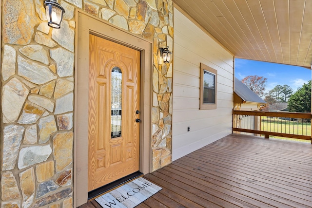 view of exterior entry featuring stone siding and a wooden deck