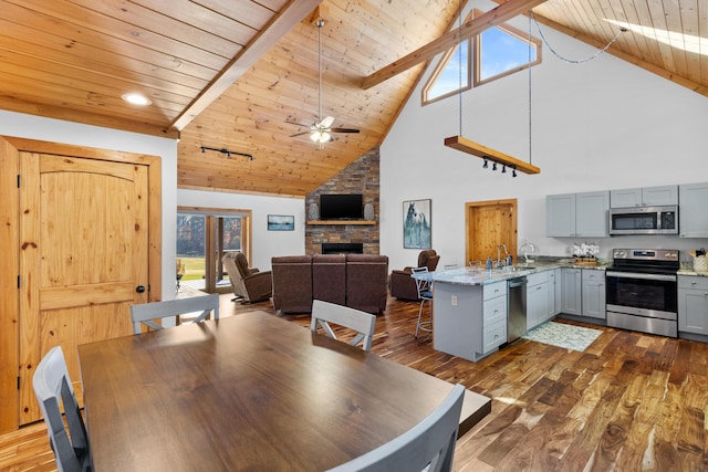 dining room featuring ceiling fan, high vaulted ceiling, a fireplace, dark wood finished floors, and wooden ceiling