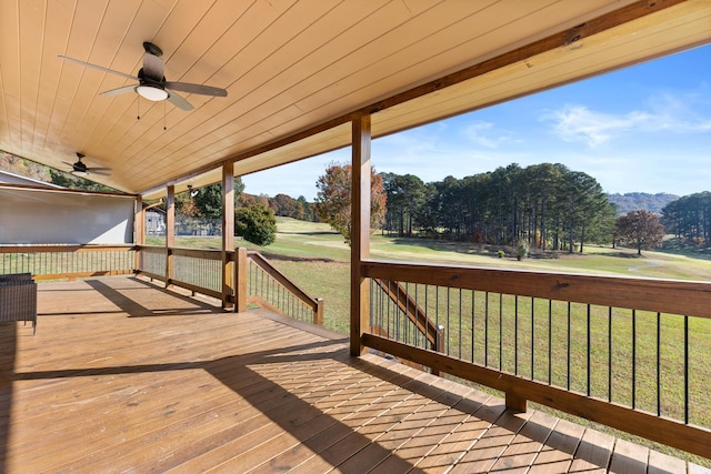 wooden deck featuring a mountain view, ceiling fan, and a lawn