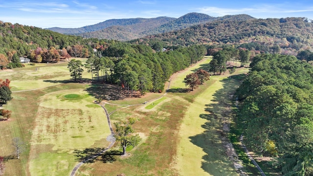 aerial view with a wooded view, a mountain view, and view of golf course