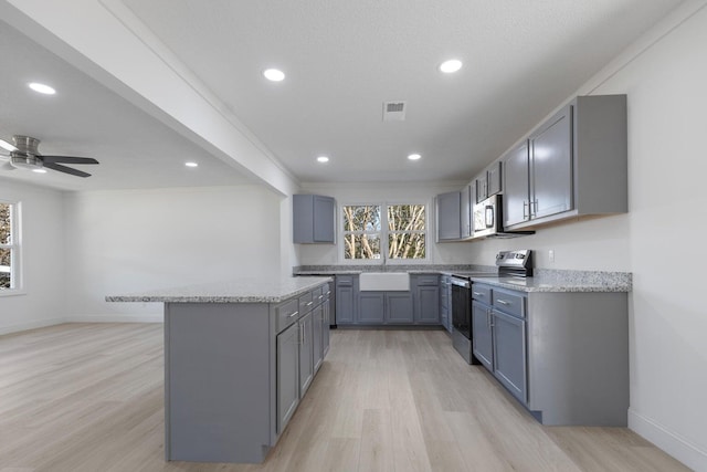 kitchen featuring a center island, light wood-style flooring, a sink, and appliances with stainless steel finishes
