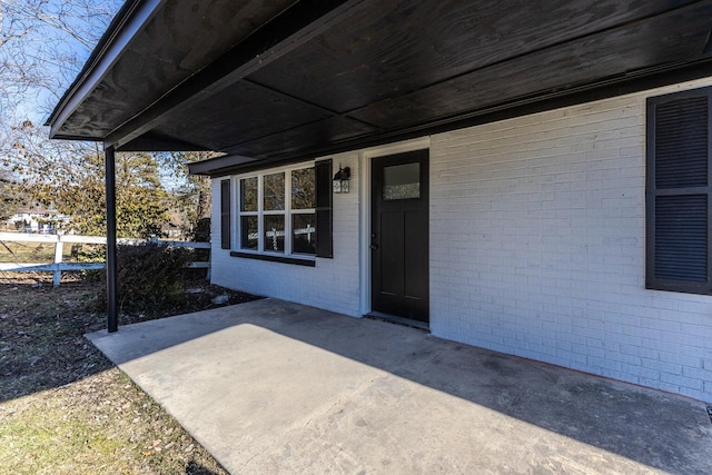 property entrance with a patio area and brick siding