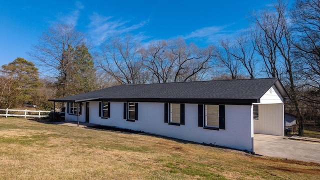 ranch-style house with fence, roof with shingles, a front yard, and brick siding