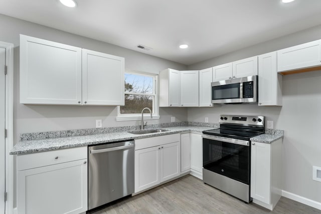 kitchen with white cabinetry, sink, light hardwood / wood-style floors, and appliances with stainless steel finishes