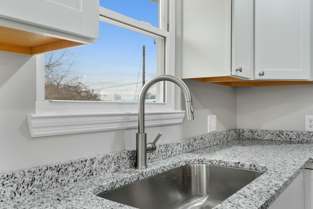 room details with light stone countertops, white cabinetry, and sink