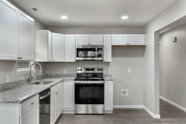 kitchen with white cabinetry, sink, dark wood-type flooring, stainless steel appliances, and light stone counters