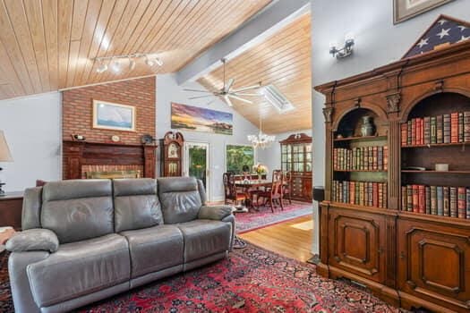 living room with ceiling fan with notable chandelier, vaulted ceiling with beams, hardwood / wood-style flooring, and wood ceiling