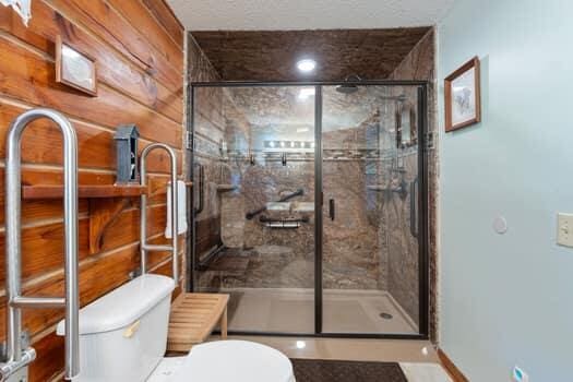 bathroom with toilet, walk in shower, and wooden walls