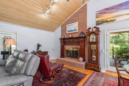 living room featuring track lighting, a brick fireplace, vaulted ceiling, wooden ceiling, and hardwood / wood-style floors