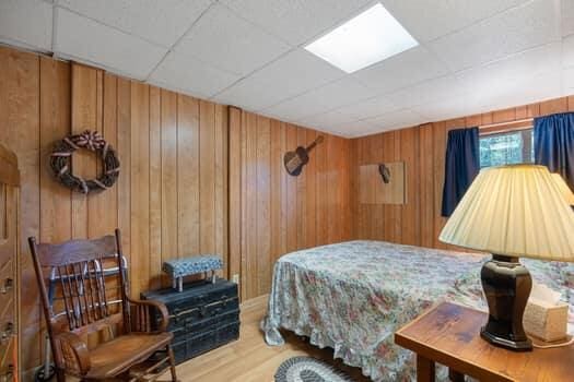 bedroom with wooden walls, a drop ceiling, and hardwood / wood-style flooring