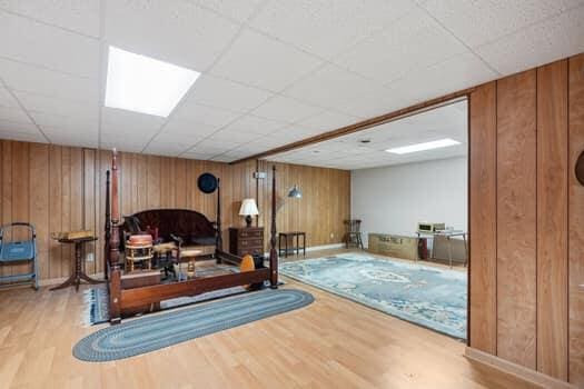 workout room with wood-type flooring, a paneled ceiling, and wooden walls