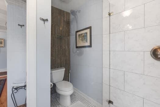 bathroom with a tile shower, tile patterned flooring, and toilet