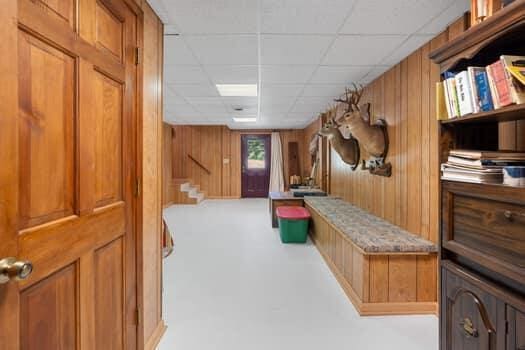 mudroom featuring a paneled ceiling and wooden walls