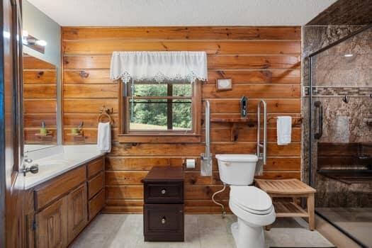 bathroom with vanity, toilet, walk in shower, and wooden walls