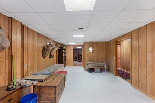 interior space featuring carpet flooring, wooden walls, and a drop ceiling