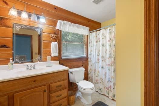 bathroom with a shower with shower curtain, vanity, wood walls, and toilet