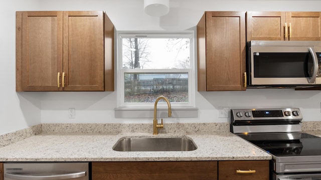 kitchen featuring light stone counters, sink, and appliances with stainless steel finishes