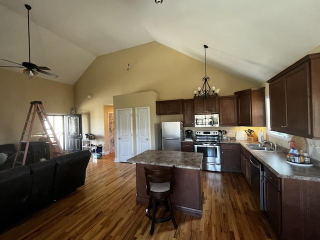 kitchen with dark wood-style floors, dark brown cabinetry, appliances with stainless steel finishes, ceiling fan with notable chandelier, and open floor plan