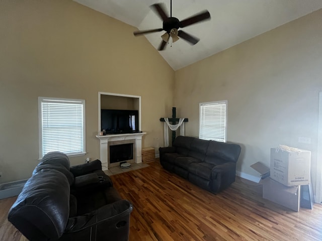 living room with a fireplace with flush hearth, high vaulted ceiling, a ceiling fan, wood finished floors, and baseboards