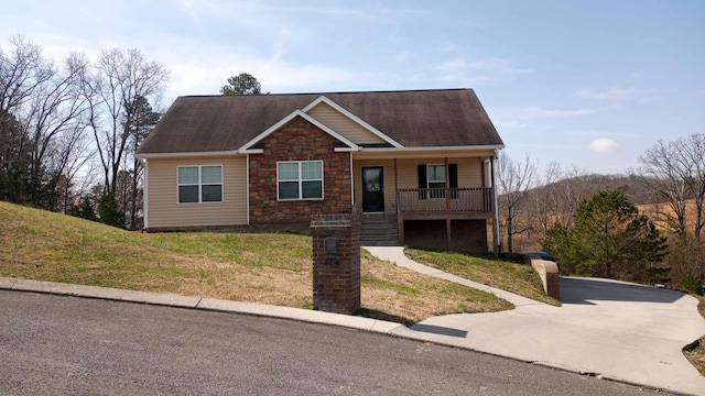 view of front of house featuring a front lawn, covered porch, stone siding, and a shingled roof