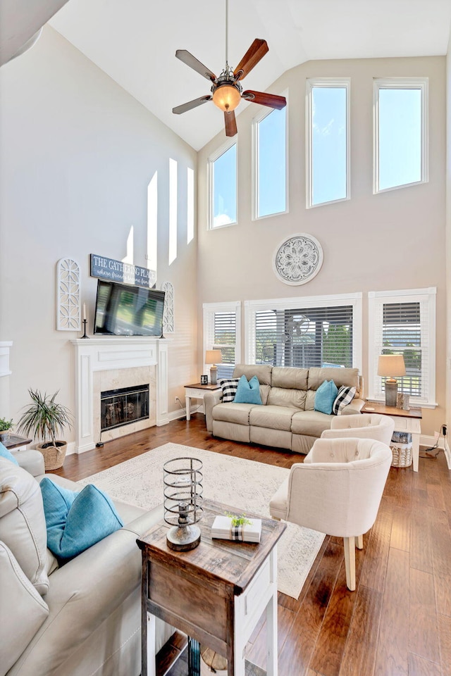 living room with a tile fireplace, wood-type flooring, high vaulted ceiling, and plenty of natural light