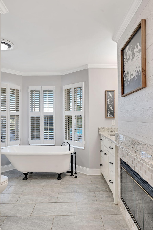 bathroom with a washtub, vanity, toilet, and ornamental molding