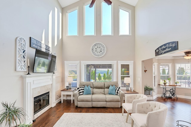 living room with ceiling fan, dark hardwood / wood-style flooring, a premium fireplace, and a wealth of natural light