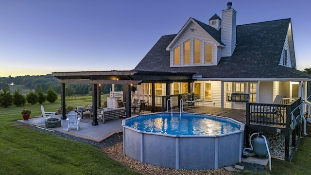 back house at dusk featuring a swimming pool side deck, an outdoor living space, and a yard