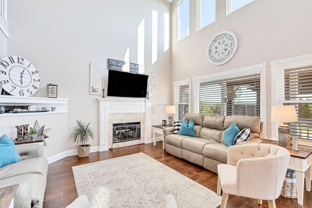 living room featuring a high end fireplace, a towering ceiling, and dark hardwood / wood-style floors