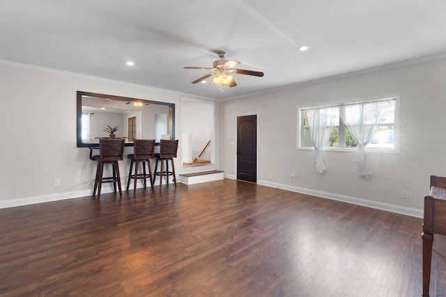 living room featuring dark hardwood / wood-style floors, ceiling fan, ornamental molding, and indoor bar