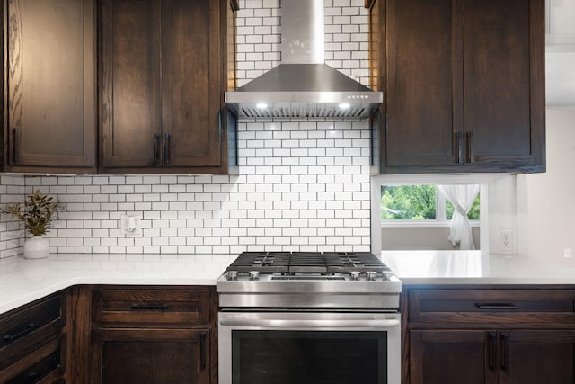 kitchen featuring backsplash, dark brown cabinetry, stainless steel range, and wall chimney range hood