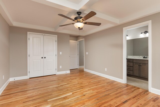 unfurnished bedroom with ensuite bath, ceiling fan, beam ceiling, light hardwood / wood-style floors, and a closet