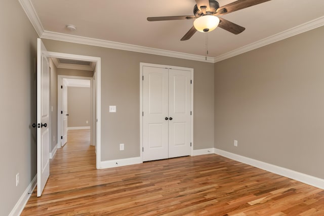 unfurnished bedroom featuring ceiling fan, a closet, light hardwood / wood-style floors, and ornamental molding