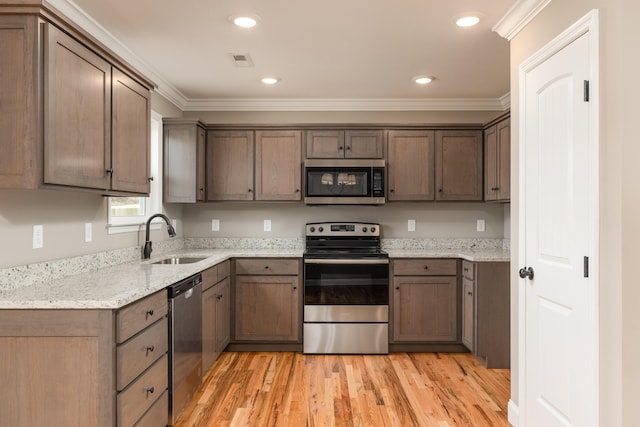 kitchen with sink, light stone counters, light hardwood / wood-style floors, appliances with stainless steel finishes, and ornamental molding