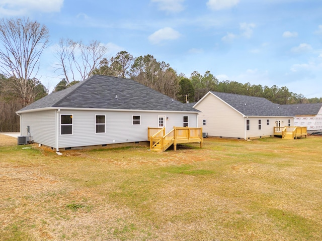 rear view of property featuring central air condition unit, a wooden deck, and a lawn