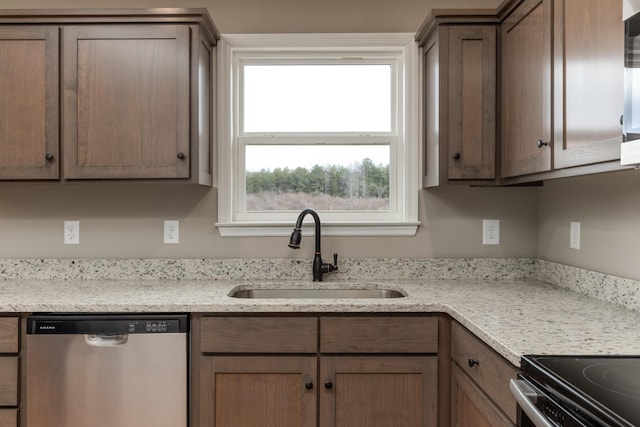 kitchen with dishwasher, light stone countertops, and sink