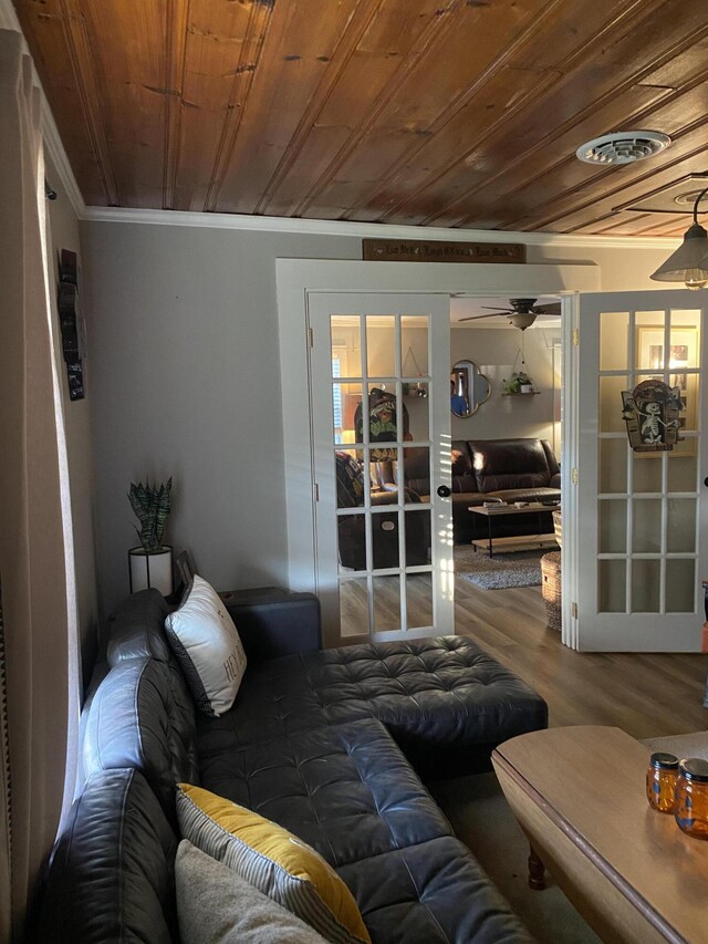 living area featuring a ceiling fan, wood ceiling, ornamental molding, wood finished floors, and french doors