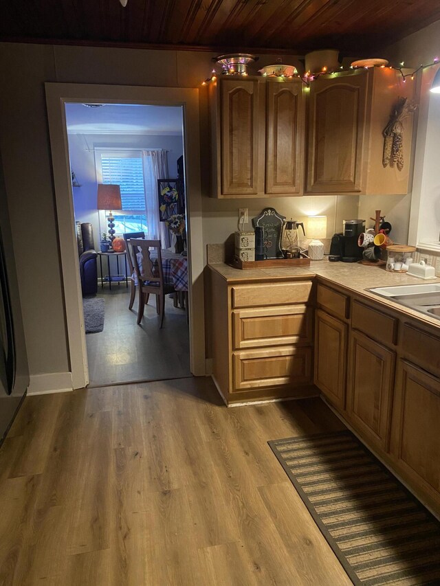 kitchen with a sink, wood ceiling, light countertops, and wood finished floors