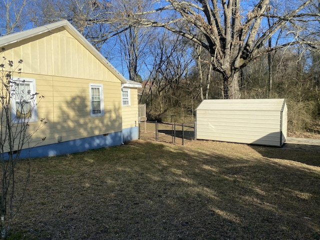 view of side of property with an outbuilding, a lawn, crawl space, a gate, and fence