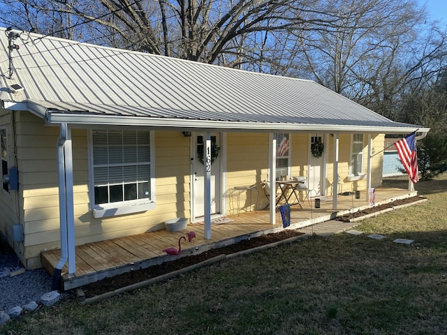 exterior space featuring covered porch, metal roof, and a front lawn