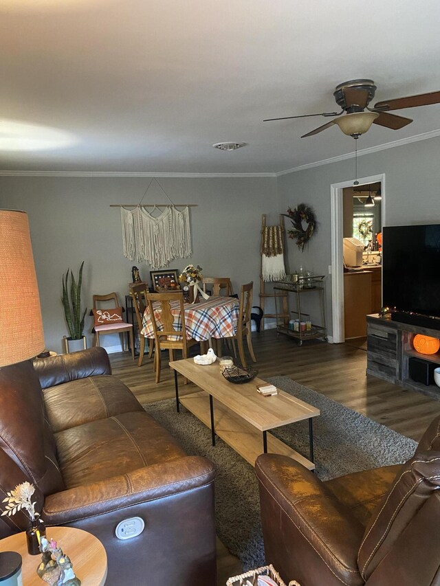 living room featuring crown molding, visible vents, a ceiling fan, and wood finished floors