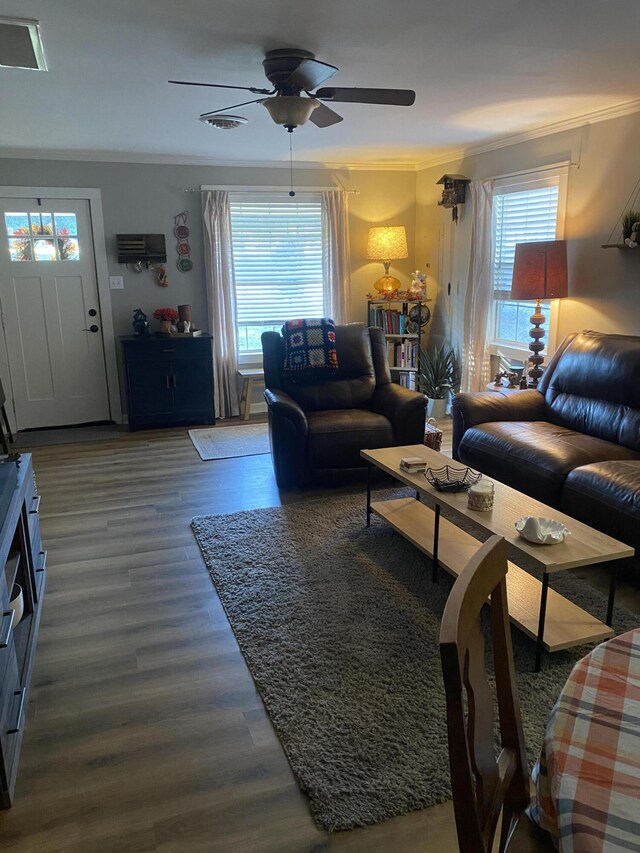 living room with plenty of natural light, ceiling fan, crown molding, and wood finished floors