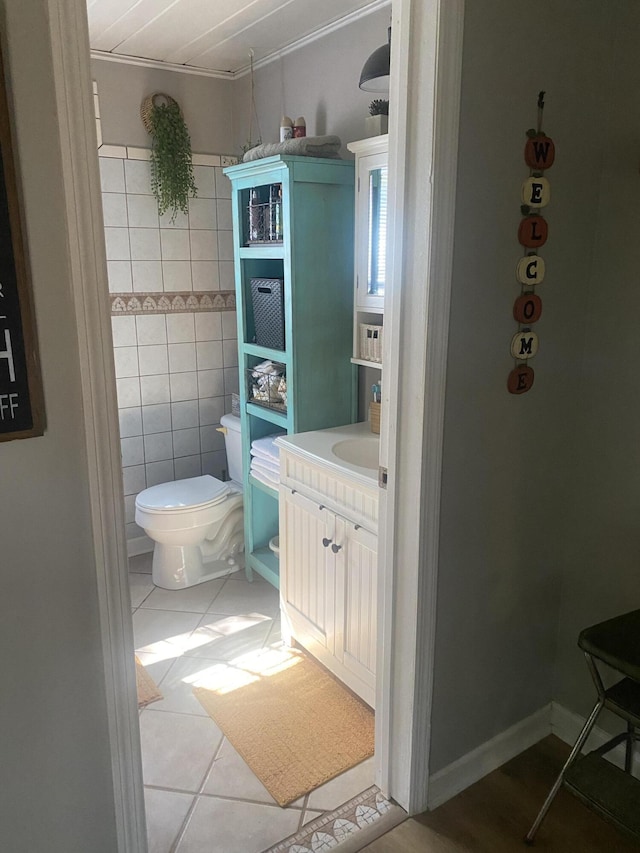 bathroom featuring toilet, tile patterned flooring, tile walls, and vanity